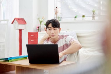 Genç Asyalı Adam Parlak Modern Oturma Odasında Dizüstü bilgisayar ve Klasörlerle Çalışıyor