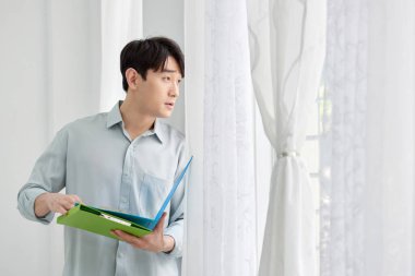 Genç Asyalı Adam Parlak Modern Ofiste Yeşil Dizini Tutuyor