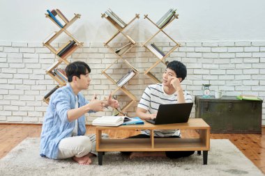 Genç Asyalı Adamlar Parlak Modern Odada Dizüstü bilgisayar ve Kitaplarla Birlikte Çalışıyor