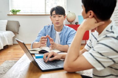 Genç Asyalı Adamlar Parlak Modern Odada Dizüstü bilgisayar ve Kitaplarla Birlikte Çalışıyor