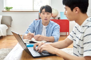 Genç Asyalı Adamlar Parlak Modern Odada Dizüstü bilgisayar ve Kitaplarla Birlikte Çalışıyor