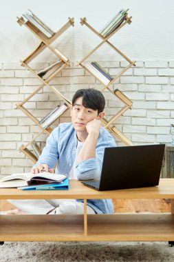 Genç Asyalı Adam Bright Modern İçişleri 'nde Laptop ve Kitaplarla Çalışıyor