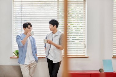 Parlak Modern Oturma Odasında Genç Asyalı Erkekler Kahve ve Sohbet Ediyor