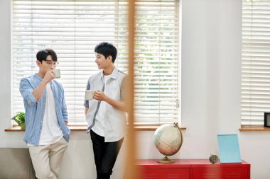 Parlak Modern Oturma Odasında Genç Asyalı Erkekler Kahve ve Sohbet Ediyor