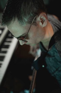 Müzik yapımcısı kendi stüdyosunda yeni bir proje kaydederken elektro gitarla akor tıngırdatıyor.