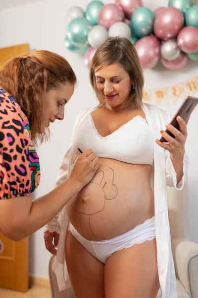Zwangere Vrouw Houdt Haar Telefoon Terwijl Een Kunstenaar Schildert Haar — Stockfoto