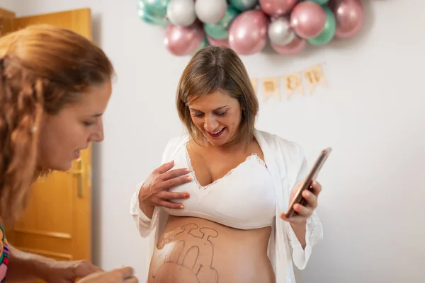 Беременная Женщина Смотрит Картину Животе Дома — стоковое фото