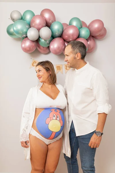 Pregnant woman with her belly painted posing with her husband at home