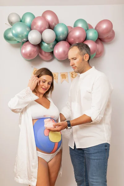 A pregnant woman with her belly painted posing next to her husband at home