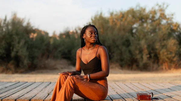 Uma Mulher Negra Jovem Com Tranças Cabelo Relaxa Descansa Sentada — Fotografia de Stock