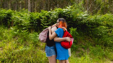 İki kız arkadaş, bir çift, birbirlerine sevgiyle sarılırlar ve yazın doğa yürüyüşü sırasında mutlu olurlar.