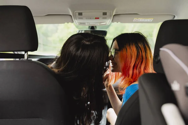 Two young lesbian women kiss inside the car during a car trip