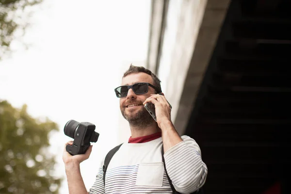 在西班牙的一个城市 一个戴着太阳镜 拿着相机 用智能手机在街上聊天的年轻人 — 图库照片