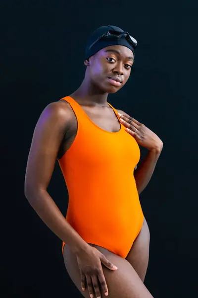 Portrait of a black young woman in swimsuit posing with plain black background