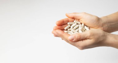 Bir kadının ellerinde bir sürü multivitamin kapsülü, besin takviyesi, beyaz arka planda, kopyalama alanı olan