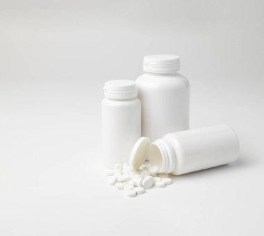 Aspirin şişelerinin bir kopyası, farklı boyutlarda, bir tanesi beyaz arka planda, kopyalanmış.