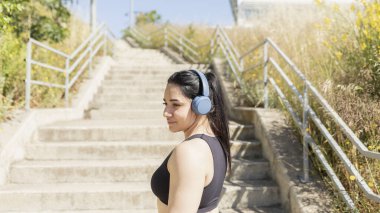 Bir kadın merdivenleri tırmanarak yarışa başlamadan önce zihinsel olarak müzik dinler, Zaragoza, İspanya