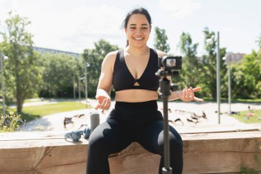 Genç bir kadın, takipçilerine egzersiz ve spor egzersizlerinin nasıl yapıldığını açıklamak için kendini videoya kaydediyor.