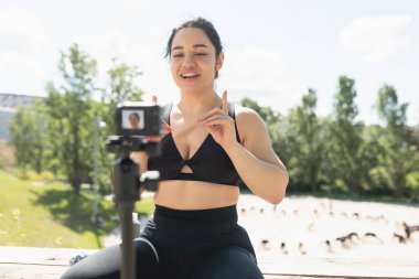 Genç bir kadın, takipçilerine egzersiz ve spor egzersizlerinin nasıl yapıldığını açıklamak için kendini videoya kaydediyor.