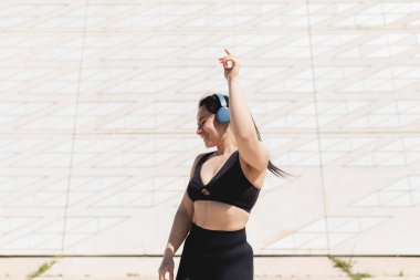 Genç bir kadın, dans ediyor, hareket ediyor, mutlu, kulaklıkla müzik dinliyor ve egzersiz yaptıktan sonra rahatlıyor.