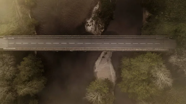 A bridge crossing the Dordogne river in the mist, aerial view by drone - France