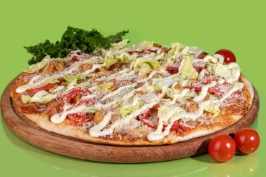 Pastırma peynirli pizza ve ahşap bir tabakta peynir ve vişneli domates. Renkli bir arka planda. Boşluğu kopyala