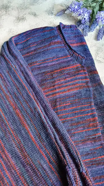 Handmade knitted products. Knitted cardigan made of purple and red threads. Gray background. Copy space