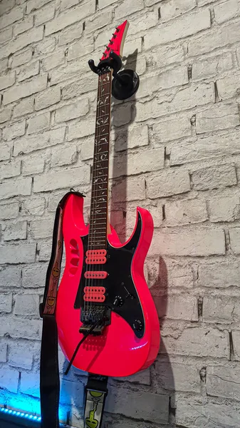 Electric guitar. Red musical instrument on a concrete wall. Copy space
