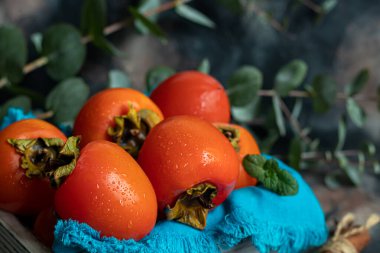 Karanlık bir arka planda hurma. Taze, olgun meyveler mavi bir tabakta ve bir kutuda. Sağlıklı beslenme.