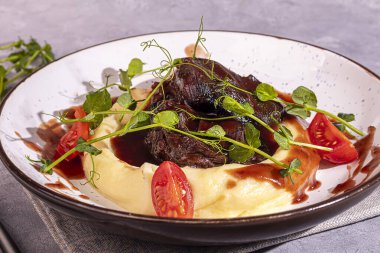 Kemiğin üzerinde kırmızı sos ve vişneli domatesle patates püresi ile sığır eti. Boşluğu kopyala