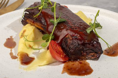 Kemiğin üzerinde kırmızı sos ve vişneli domatesle patates püresi ile sığır eti. Boşluğu kopyala