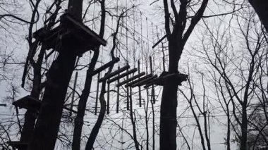 Ağaçların üzerindeki parktaki engelli parkurda askıya alındı. İplerle havada tahtalar. Çekicilik. Soğuk