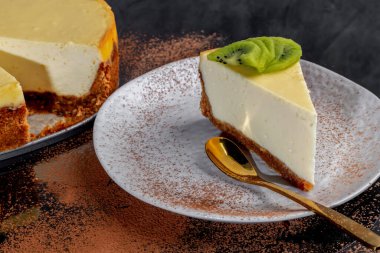 Masada süzme peynirli nefis peynirli kek, kivi ile süslenmiş. Karanlık bir arka planda. Ev yapımı pişirme. Boşluğu kopyala