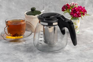 İçinde metal süzgeç olan cam çaydanlık. Mutfak aletleri gri arka planda. Boşluğu kopyala