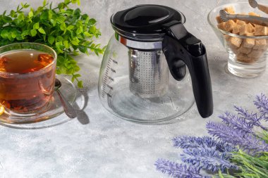 İçinde metal süzgeç olan cam çaydanlık. Mutfak aletleri gri arka planda. Boşluğu kopyala