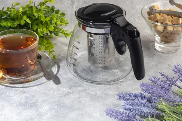 İçinde metal süzgeç olan cam çaydanlık. Mutfak aletleri gri arka planda. Boşluğu kopyala