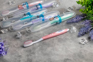 Gri arka planda plastik ambalajlı diş fırçaları. Satılık. Boşluğu kopyala