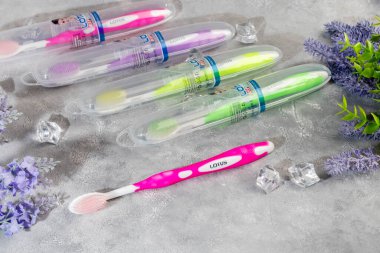 Gri arka planda plastik ambalajlı diş fırçaları. Satılık. Boşluğu kopyala