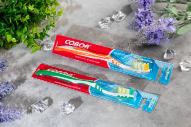 Gri arka planda plastik ambalajlı diş fırçaları. Satılık. Boşluğu kopyala