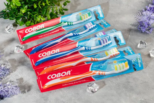 Gri arka planda plastik ambalajlı diş fırçaları. Satılık. Boşluğu kopyala