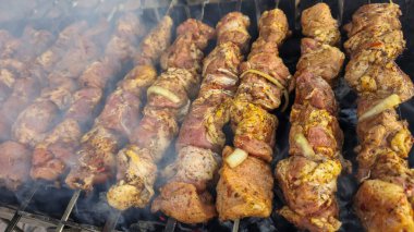 Şişler üzerinde marine edilmiş et parçaları ızgarada yatıyor ve kömürde kızartılıyor. Domuz shashlik pişiriyorum. Açık hava eğlencesi
