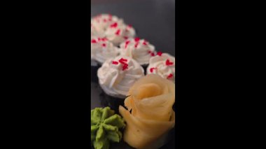 Philadelphia peynirli suşi, avokado, ton balığı ve karides, üstüne de tatlı ve ekşi sos. Siyah bir arka planda. Yemek fotoğrafçılığı