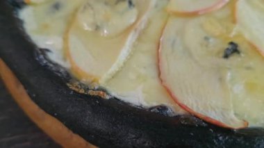Mürekkep balığı mürekkebi armut peyniriyle ballı siyah hamurdan pizza. Siyah bir arka planda. Restoranlar için menü