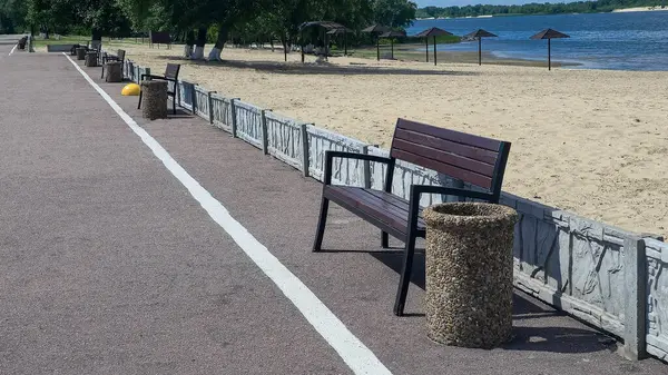 Ahşap banklar ve çöp kutuları yolun kenarında park dinlenme alanında. Yaz