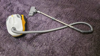 Odayı temizledikten sonra leylak bir halının üzerindeki elektrikli süpürge. Uzun hortum, ıslak temizlik. Toz toplayıcı.