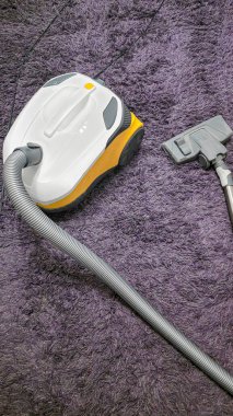 Odayı temizledikten sonra leylak bir halının üzerindeki elektrikli süpürge. Uzun hortum, ıslak temizlik. Toz toplayıcı.