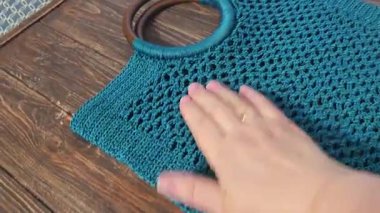 Yeşil ipliklerden yapılmış bir örgü çantasının buhar tedavisi. Tahta bir arka planda çanta. El yapımı.