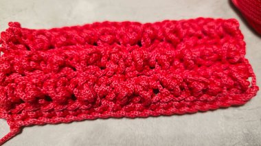 Bir çanta için örgü deseni. Kırmızı polyester kablodan örülmüş. Gri bir arka planda. Desenli tasarım