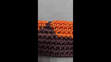 Çantanın elementleri kahverengi ve turuncu kablodan örülmüş. Tahta bir üste. El yapımı.