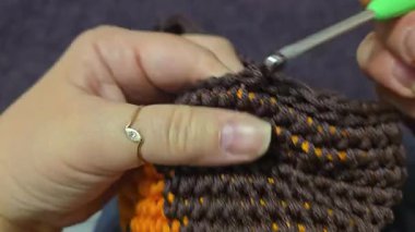 Çantanın elementleri kahverengi ve turuncu kablodan örülmüş. Tahta bir üste. El yapımı.